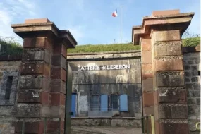 Entrée de la Batterie de l'Éperon dans le Bassin de Pompey en Meurthe-et-Moselle. Deux grands piliers en pierre encadrent la façade fortifiée aux volets bleus, surmontée d'un drapeau français